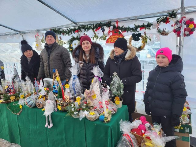 grupa piuęciu osób przed nimi stół z dekoracjami świątecznymi