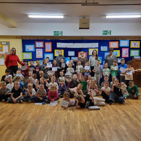 dzieci stoja na sali z pisarka