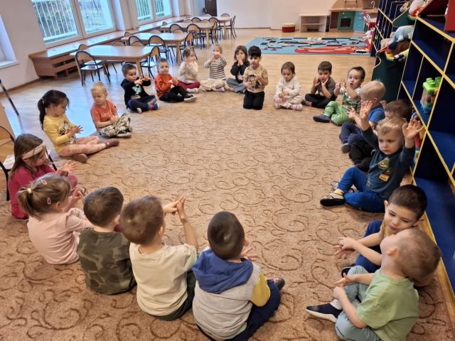 Dzieci siedza na dywanie pokazują palce